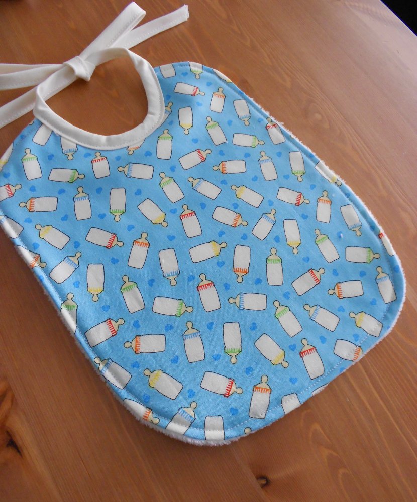 Bavaglino bambino in 100% cotone. Tessuto azzurro con biberon.