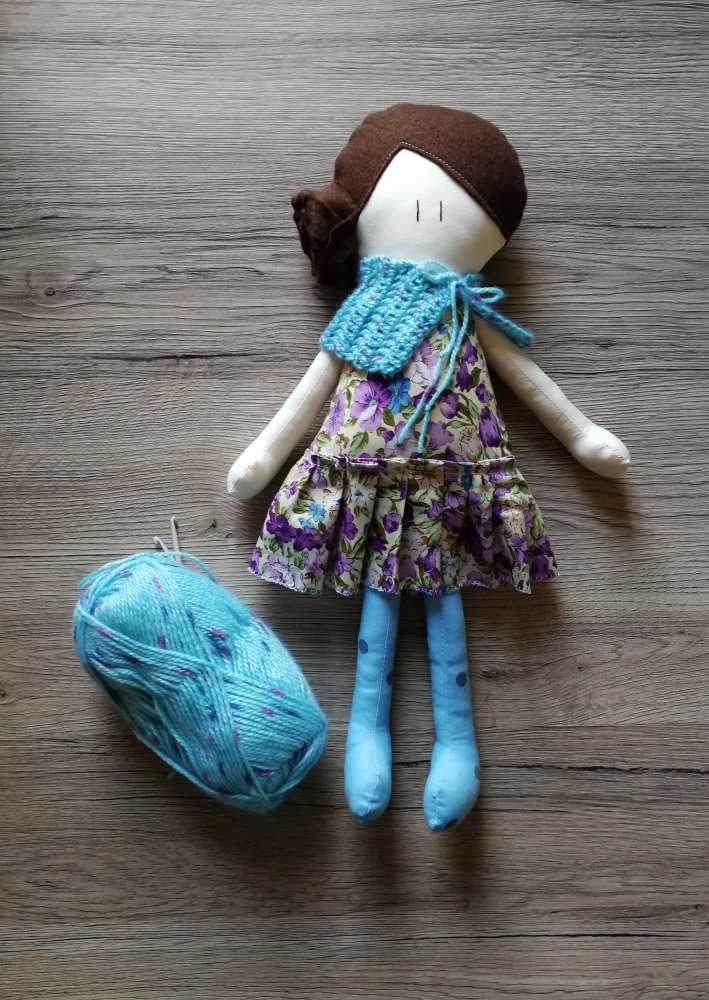 Bambola di stoffa Amicoccola con vestito in fantasia floreale viola e accessori in lana azzurri con sfumature viola